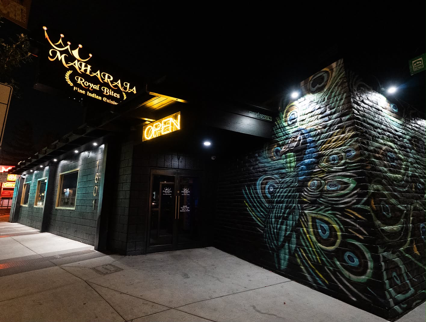 Maharaja Royal Bites storefront at night with a painted peacock mural